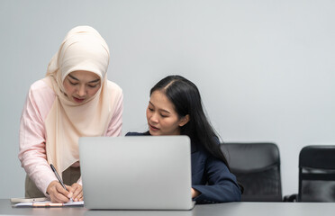 Professional business discussion between two female colleagues using laptop in modern office,...