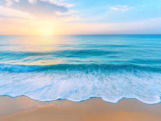 Obraz premium Tropical ocean wave rolling onto sandy beach at sunrise with turquoise water and peaceful morning sky over tranquil seascape.