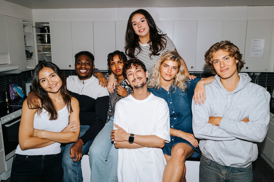 Portrait of multiracial male and female friends posing in dorm room kitchen