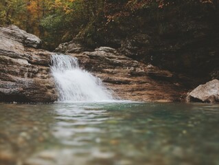 Tranquil forest waterfall cascading over rocky ledges in autumn