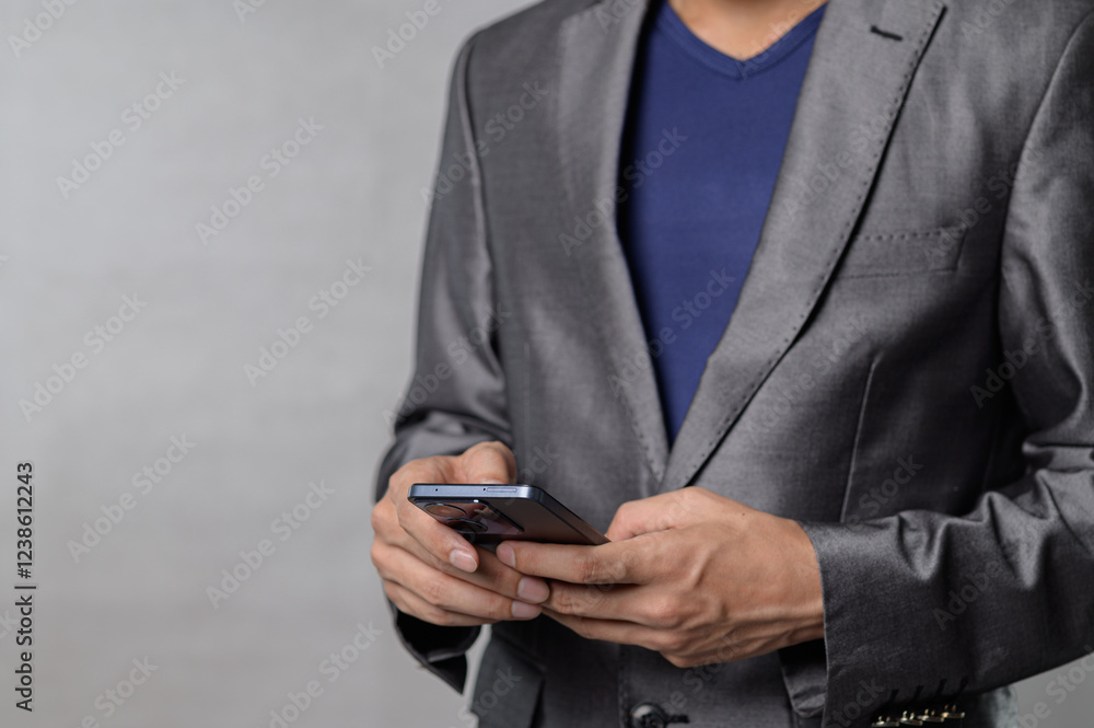 Poster man in suit using smartphone with gray background for business focus