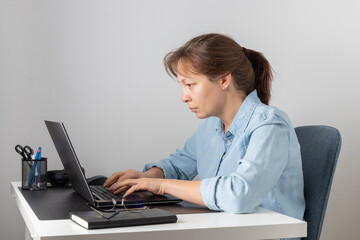 A stressful woman typing on the keyboard using laptop, looking at PC screen, remote hardworking stooped freelancer works from home. Incorrect posture, bad habit