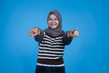Happy Young Woman Pointing Both Hands Forward in a Blue Background