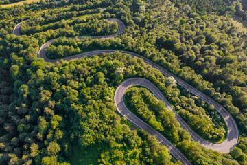 Aerial summer view of a winding mountain road through green forest