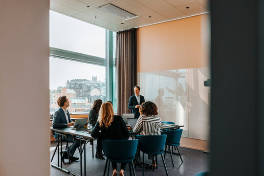Male entrepreneur taking team meeting with colleagues in board room at office