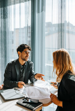 Male client talking with businesswoman while doing paperwork at office