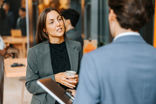 Businesswoman discussing with male entrepreneur during networking event at convention center