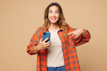 Young shocked surprised woman she wear orange shirt casual clothes hold in hand use point finger on...