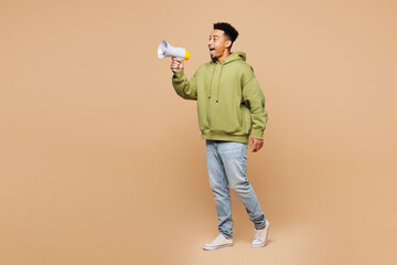 Full body young shocked happy man wears green hoodie casual clothes hold in hand megaphone scream...