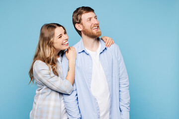 Fototapeta premium Young couple two friends family man woman wear shirt casual clothes cuddle embrace look aside on area blank area together isolated on pastel plain light blue cyan background studio. Lifestyle concept.