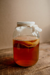 Fresh kombucha in a glass jar on a wooden background.
