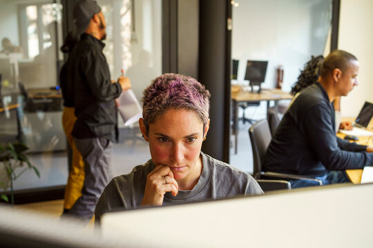Focused non-binary computer programmer working in office