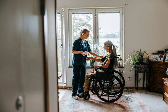 Female medical expert checking blood pressure of elderly woman with disability at nursing home