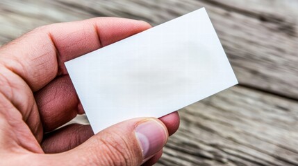 Blank business card held by a hand with wood background texture