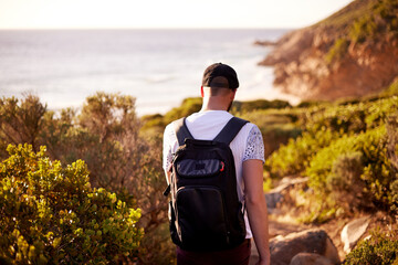 Fototapeta premium Walking, travel and back with man in nature for hiking, adventure and summer vacation. Trekking, tour guide and eco tourism with person outdoors for environment, wildlife reserve and backpacking