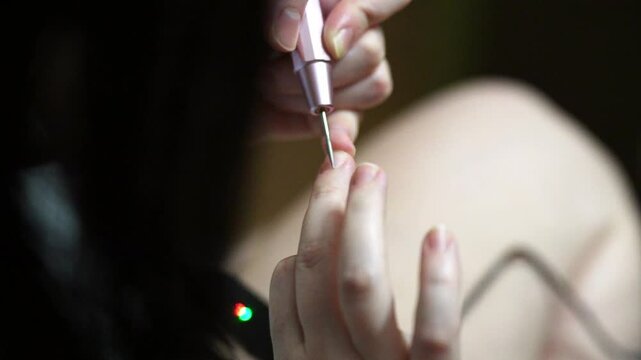woman hands using a nail buffer on her nails after cuticle removal, showcasing a professional manicure process in slow motion