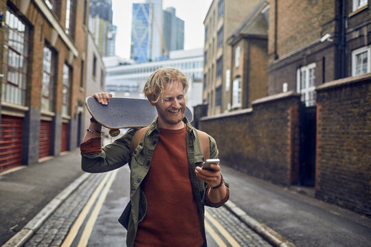 Young redhead man using a smart phone on a city street