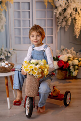 Happy beautiful child,  kid,  playing with small beautiful knitted chick, spring flowers and bike