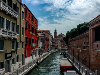 A Peaceful Venetian Canal winds through the city, lined with lush greenery and charming buildings. Boats glide along the water, creating gentle ripples. 