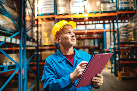 Warehouse supervisor inspecting inventory with clipboard in storage facility