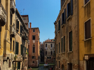 A Glimpse Down a Venetian Canal. A narrow canal winds its way through the city, lined with colorful buildings that lean in towards each other..
