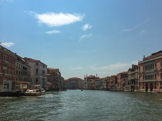 A Glimpse Down the Grand Canal. The Grand Canal stretches into the distance, lined with colorful buildings and dotted with boats. The sky is a brilliant blue with fluffy white cloud. 