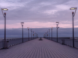 Ocean Pier at Dusk with Streetlights and Cloudy Sky
