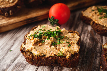 Rustic Pate, man smear on Black Bread with Fresh Herbs and tomatoes