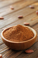 cocoa powder in bowl and raw cocoa beans on table