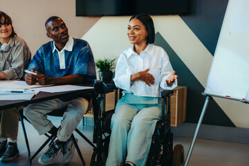 College students in an inclusive classroom setting with disabled student participating in group discussion at university