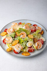 Caesar salad with tiger prawns, cherry tomatoes, croutons, parmesan cheese, quail eggs and romaine lettuce. Traditional American dish. Close-up, selective focus.