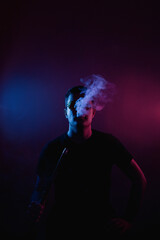 Silhouette of a man wearing glasses enjoying a serene moment surrounded by flickering smoke in a bright neon light in a hookah bar