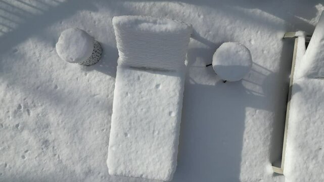 aerial view of snow covered lounge chairs next to closed shuttered swimming pool in winter (back yard patio loungers outdoor furniture) spa bizzard snowy snowfall frozen home countryside drone footage