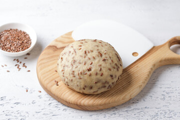 Lenten vegan raw dough with flax seeds on a wooden board on a light blue background with copy space. Healthy homemade food concept