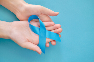 Blue symbolic tape on two hands - sclerosis, sexual slavery, colon cancer, chronic fatigue on a blue background