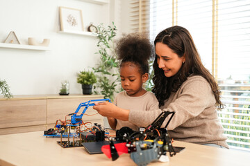 Happy mother guiding her young daughter in assembling a robotic arm, engaging in a fun and educational STEM activity, fostering creativity and learning at home