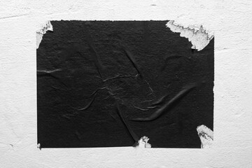 Torn black poster on white wall.