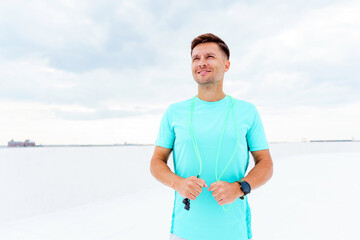 Man in turquoise shirt stands on snowy landscape, enjoying winter outdoor sports in tranquil setting