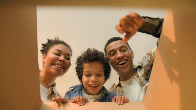 POV point of view inside cardboard box African American family parents little boy kid child open unpack parcel online shopping delivery happy excited mother father son unboxing unpacking moving day