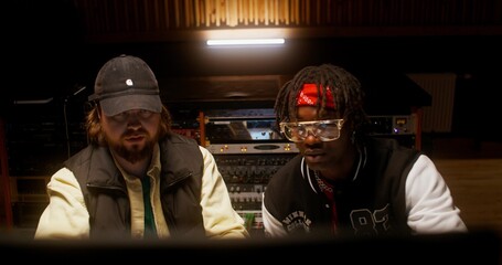 Listening to the song after recording in the studio. The sound engineer and the performer are...