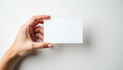 Obraz premium A hand delicately holds a blank white card, offering space for your message or design.