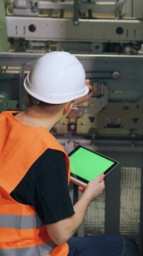 A male elevator repairman enters data on the operation of equipment into a digital tablet. Inventory of elevator equipment parts, performance check.