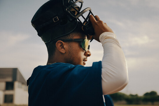 Baseball player adjusting helmet visor during practice on the field