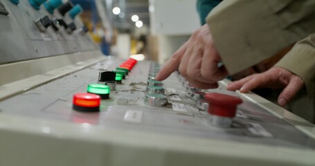 Two men use the control panel of the machines in the factory. Close-up of their hands, an unrecognizable person