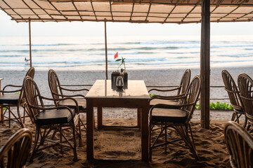 Restaurant mit Tisch und Stühlen, die in Sand stehen am Strand in Goa bei Sonnenuntergang