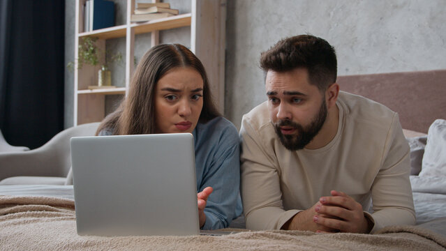 Caucasian upset couple husband wife worried shocked disappointed bad news loss negative result breakdown laptop internet service displeased woman girl and man guy in bedroom computer addicted failure