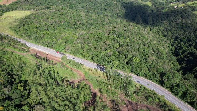 Ve&iacute;culos trafegando em uma estrada vicinal no interior de S&atilde;o Paulo, em uma estrada que corta a vegeta&ccedil;&atilde;o.