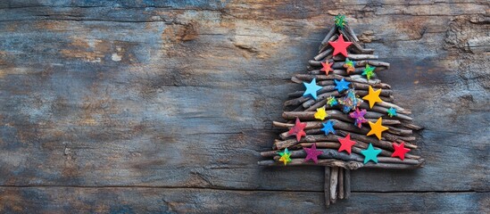 Fototapeta premium Wooden Christmas tree made of branches decorated with colorful stars on rustic wooden background.