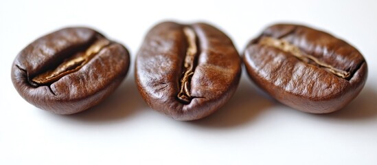 Obraz premium Close-up of three roasted coffee beans on white background with soft shadows
