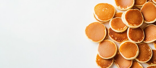 Stack of golden brown mini pancakes on a white background with copy space.